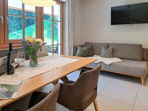 A dining area with a wooden table, chairs, a vase with flowers, and a bottle. - Chalet Edelweiß by Interhome (Auffach)