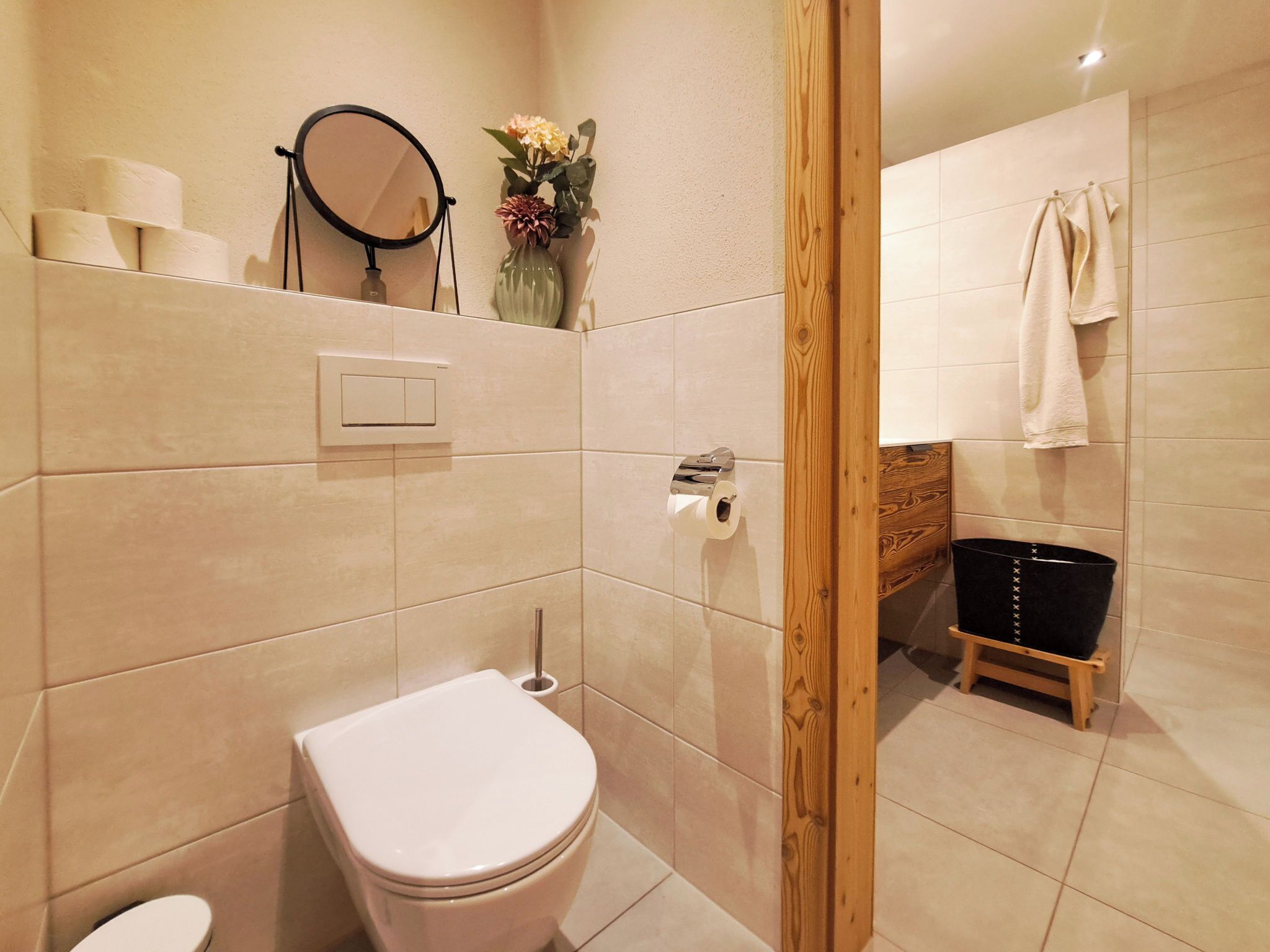 Une salle de bain équipée de toilettes, d’un porte-serviettes et d’un tabouret en bois.