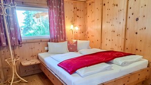 Una habitación de madera con una cama, cortinas, una mesita de noche y una lámpara.