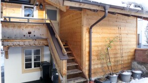 Una cabaña de madera con una escalera de madera que lleva a un entrepiso, una ventana pequeña y una puerta.