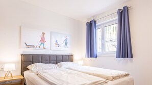 A bedroom with a bed, a nightstand, a lamp, and a window with curtains. - für bis zu 8 Personen + Hot Tub by Interhome (Turracher Höhe)