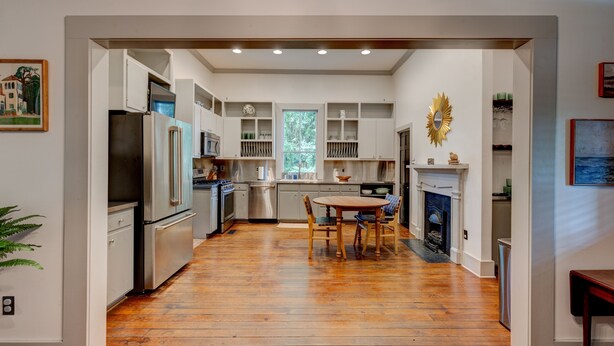 Una cocina moderna con suelo de madera, armarios empotrados, una isla central y una chimenea.