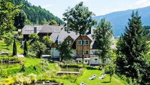 Un hotel sul lago con una terrazza in legno, un piccolo stagno e poltrone da relax.