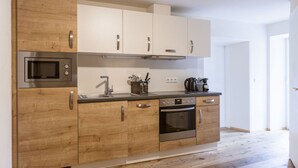 Una cucina moderna con mobili in legno, forno a microonde integrato, macchina da caffè e lavastoviglie.