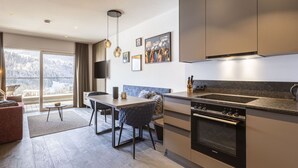 A modern kitchen with a built-in oven, a dining area with a table and chairs, and a large window offering a view of the outdoors. - mit 1 Schlafzimmer für 2-4 Personen by Interhome (Hopfgarten im Brixental)