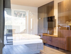 Et moderne soveværelse med en seng, et fjernsyn og et træskab.