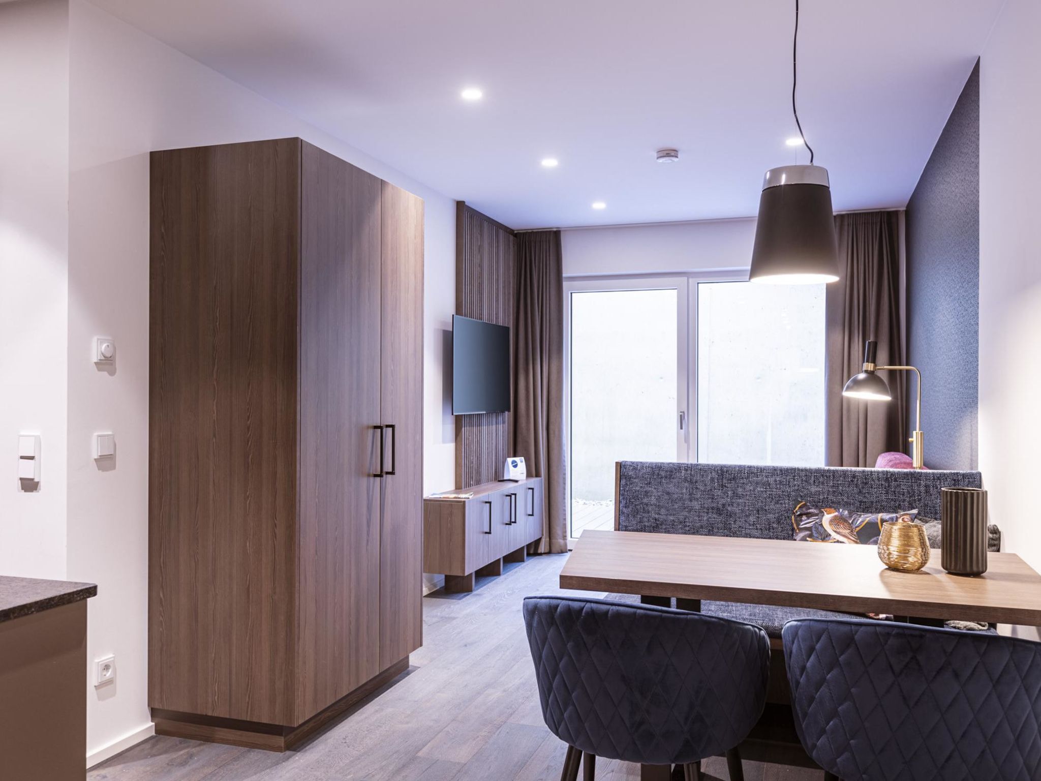 A modern kitchen with wooden cabinets, a dining table, and chairs.
