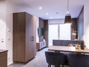 Moderni keittiö, jossa on puiset kaapit, ruokapöytä ja tuolit.