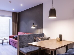 Una habitación moderna con sofá, una mesa, una lámpara y vistas por la ventana.