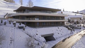 Ein mehrstöckiges Hotel mit einer Skipiste im Hintergrund.