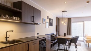 Eine moderne Küche mit Holzschränken, einem eingebauten Ofen und einem Essbereich mit Tisch und Stühlen.