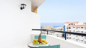 A balcony with a table set with fruit, a chair, and a view of the sea and buildings. - Home2Book Calm Ocean Los Cristianos (Los Cristianos)