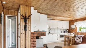 A cozy kitchen with wooden cabinets, a brick fireplace, and a dining area with a table and chairs.