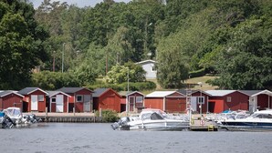 A marina with several red buildings, likely cabins or lodges, docked alongside the water.