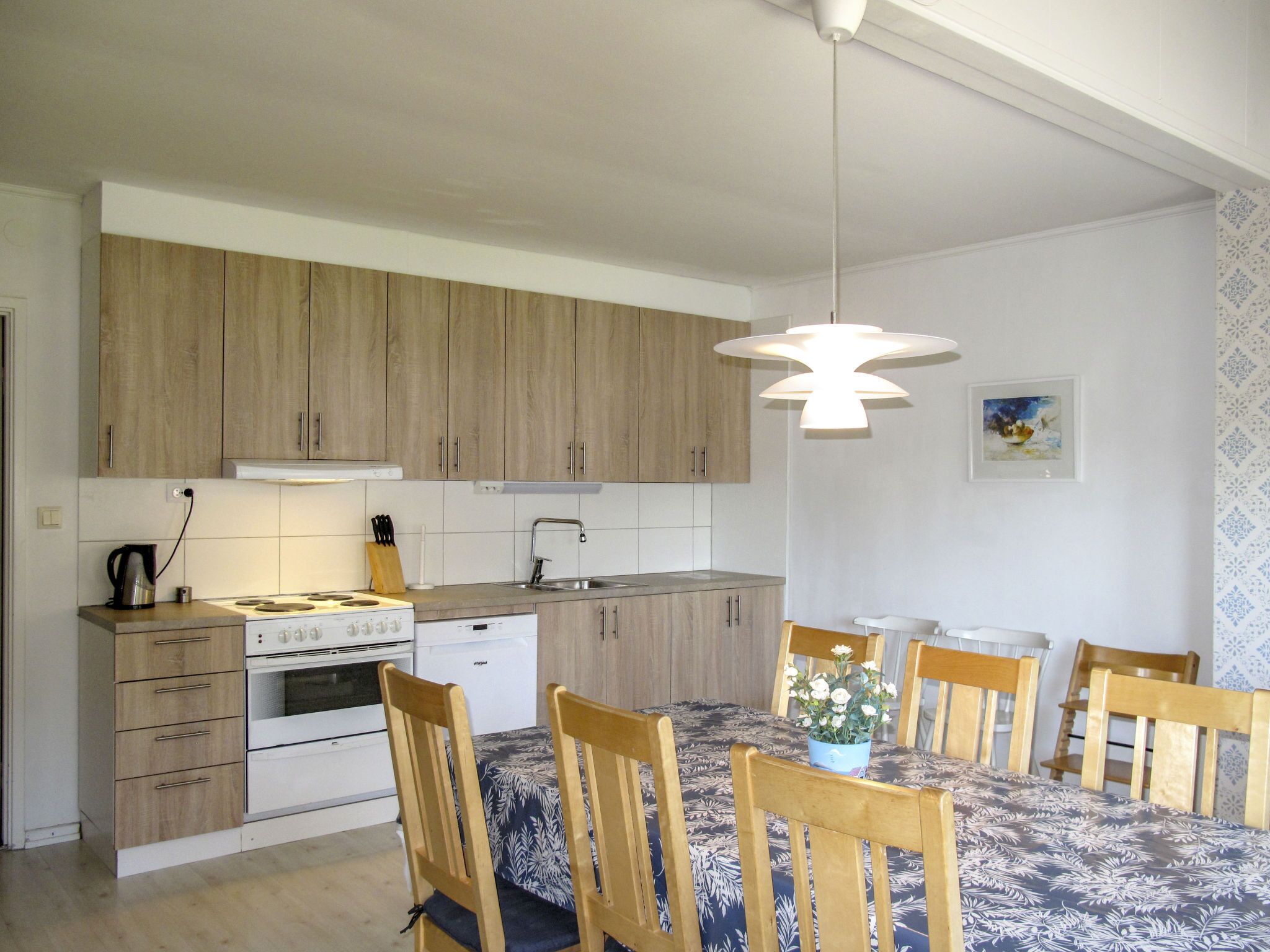Une cuisine moderne avec des meubles en bois, une cuisinière et un coin repas comprenant une table et des chaises.