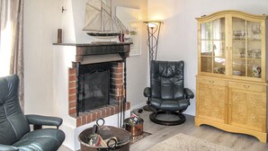 Ein Wohnzimmer mit Kamin, einem Ledersessel, einem Holzschrank und einem Schiffsmodell auf dem Kaminbrett.