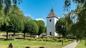 A cemetery with a white tower, stone headstones, and a gravel path. - Lindby Pärlan by Interhome (Adelsö)