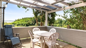 A covered patio with a table and chairs, overlooking a lush landscape. - Lindby Pärlan by Interhome (Adelsö)