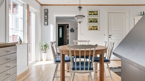 A dining area with a wooden table and chairs, a chandelier, and framed artwork on the wall. - Aspenäs by Interhome (Sandhem)