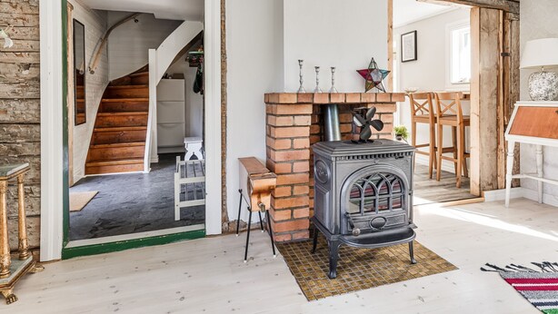 A cozy room with a brick fireplace, wooden staircase, and a white door leading to another room. - Aspenäs by Interhome (Sandhem)