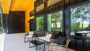 Un espacio al aire libre con mobiliario de mimbre y ventanas amplias.