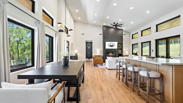 Una cocina moderna con una isla grande, taburetes de bar y amplios ventanales que dan al exterior.