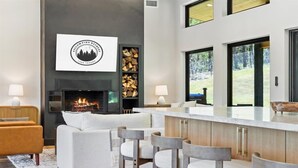 Una sala de estar moderna con chimenea, una zona de bar y un amplio ventanal con vistas al exterior.