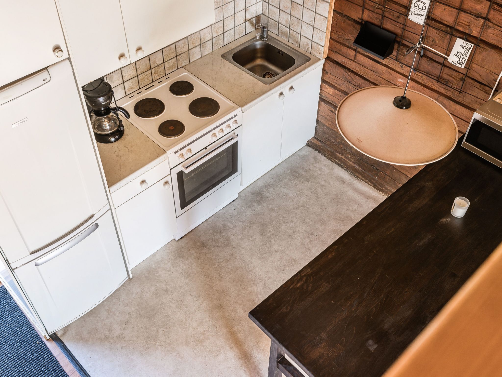 A compact kitchen with white cabinets, a built-in stove, a sink, and a microwave.