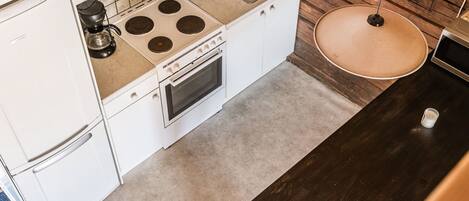 A compact kitchen with white cabinets, a built-in stove, a sink, and a microwave.