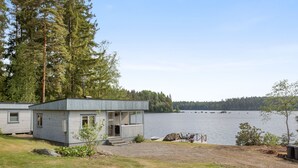 Une cabane dotée d’une terrasse donnant sur un lac, entourée d’arbres.