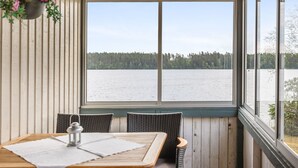 Une pièce chaleureuse avec un plafond en bois et une grande fenêtre donnant sur un lac.