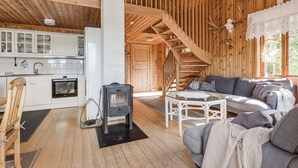 A wooden cabin interior with a kitchen, a fireplace, a sofa, and a staircase. - Kasen Sjökanten by Interhome (Färgelanda)