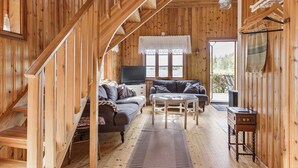 A wooden cabin interior with a staircase, a sofa, a TV, and a dining table. - Kasen Sjökanten by Interhome (Färgelanda)
