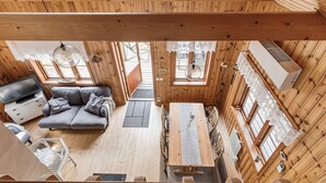 A wooden cabin interior with a sofa, dining table, and large windows. - Kasen Sjökanten by Interhome (Färgelanda)