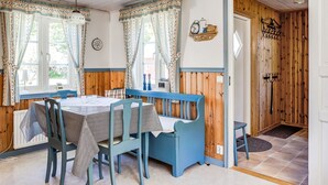 A cozy dining area with a wooden table and chairs, a window with curtains, and a door leading to another room. - Mjöhult Utsikten by Interhome (Ätran)