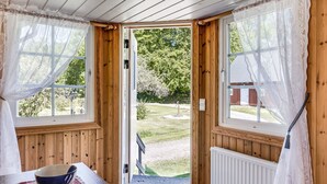 A wooden room with a large window, a door leading outside, and a table with a bowl. - Mjöhult Utsikten by Interhome (Ätran)