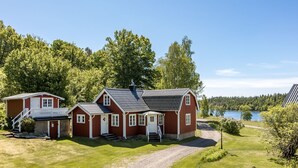 A red wooden house with a gravel driveway and a small pond in the background. - Mjöhult Utsikten by Interhome (Ätran)
