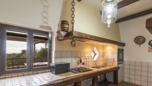 A kitchen with a wooden table, a gas stove, a hanging light fixture, and a window overlooking a scenic view.