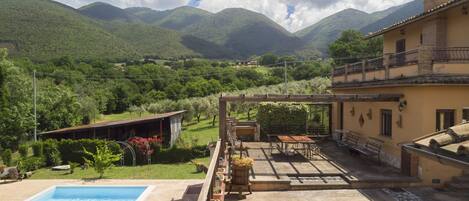 A pool area with a view of green hills and mountains in the background.