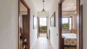 A hallway with a tiled floor leading to a bedroom with a bed and a window.