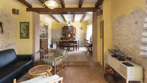A spacious living area with a fireplace, wooden beams, and a dining area with chairs and a table.