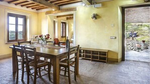 A dining area with a wooden table and chairs, a vase with flowers, and a view of the outdoors through a window. - I Limoni (BUT151) by Interhome (Buti)