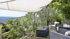 An outdoor seating area with wicker furniture and a view of the countryside. - I Limoni (BUT151) by Interhome (Buti)