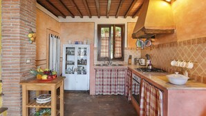 Une cuisine rustique avec un mur en briques, des poutres en bois, un pare-feu en carreaux et une fenêtre offrant une belle vue.
