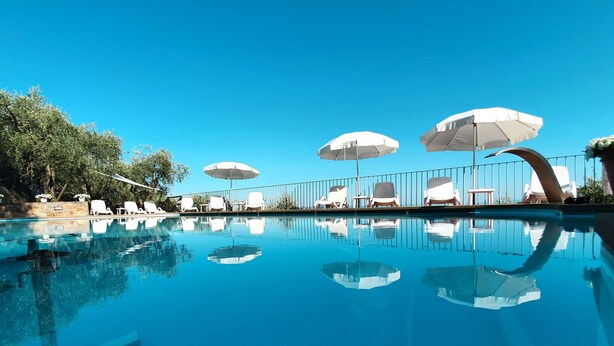 Une piscine d’un bleu éclatant, agrémentée de parasols blancs et de chaises longues.