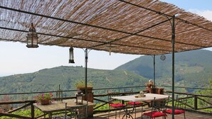 Une terrasse extérieure avec une table et des chaises, une lanterne suspendue et une vue sur un paysage montagneux.