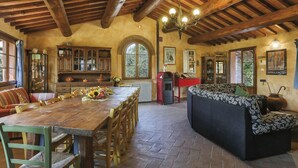 Uma área de jantar rústica com mesa e cadeiras de madeira, um sofá e um lustre.