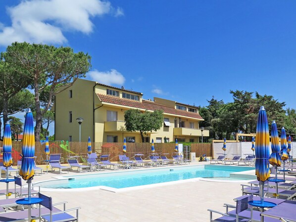 Ett hotell med en swimmingpool, solstolar och parasoller.