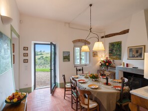 Enjoy meals in this cozy dining area with a table set for a meal, surrounded by framed artwork and a fireplace.