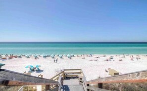 A beach with a wooden boardwalk leading to the water, umbrellas, and people relaxing on the sand. - Beach Bliss by Stay on 30a (Seacrest Beach)